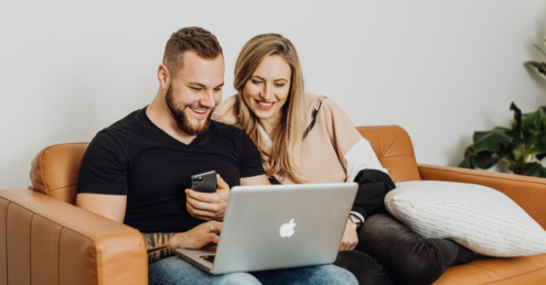 couple sitting on the sofa, looking at a laptop which is apple branded, they could be searching online what to do next when their mortgage deal ends.